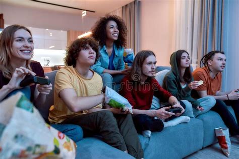 Young Multicultural People Eating Snacks Playing Video Games Stock