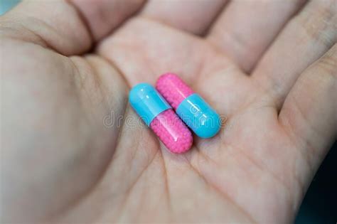 Hand Showing Blue And Pink Capsule Pill On Blurred Background Stock