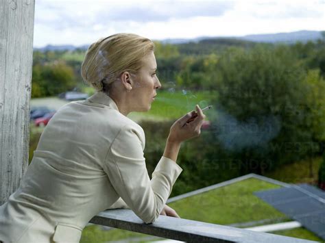 Businesswoman Smoking On Balcony Stock Photo