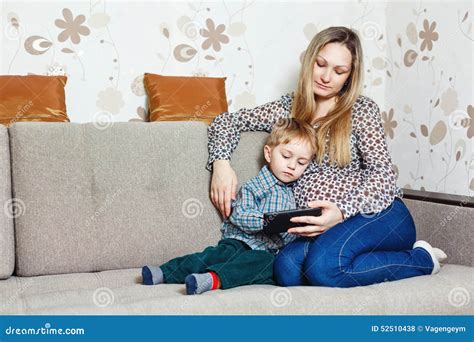 Mamá E Hijo Que Se Sientan En El Sofá Con Una Tableta Foto De Archivo Imagen De Maternidad
