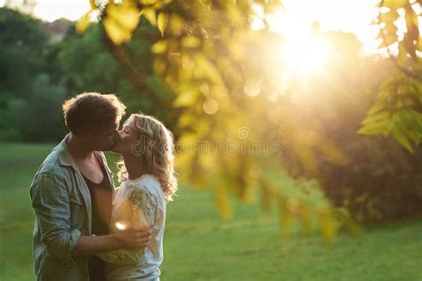 Romantic Couple Kissing Each Other At Sunset In A Park Stock Image