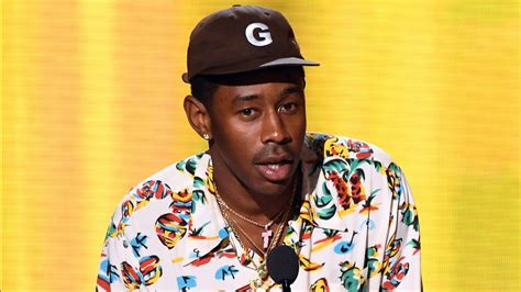 Tyler The Creator Is Wearing Colorful Shirt And Brown Cap Standing In