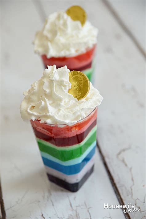 Two Rainbow Jello Cups With Whipped Cream And Gold Coins On Top