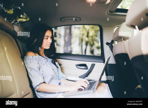 Business Woman Sitting With Laptop And Working On Backseat Of Car Stock