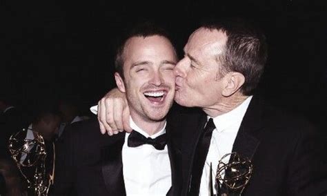 Two Men In Tuxedos Kissing Each Other At An Awards Ceremony With Their