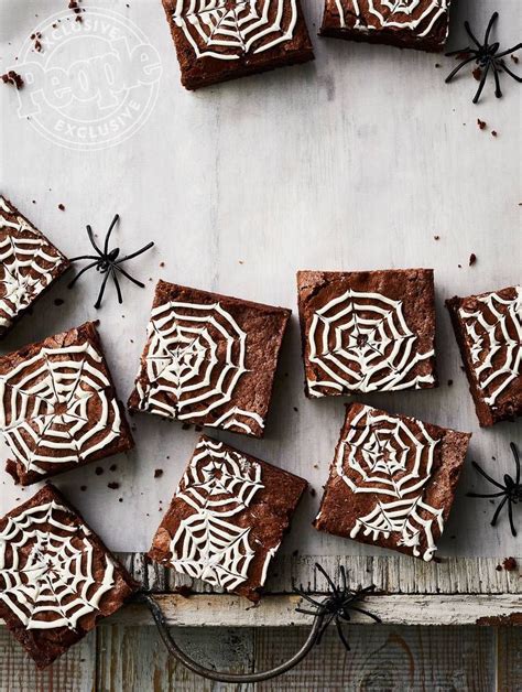 chocolate brownies with white frosting and spider webs on top sitting on a table