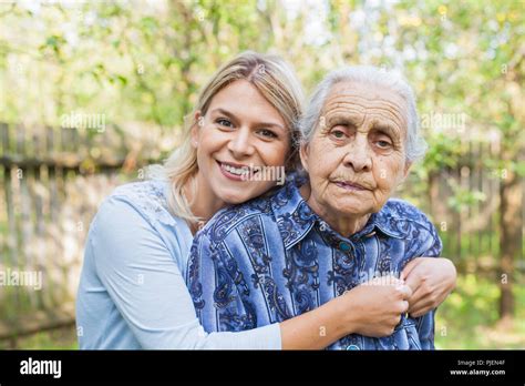 Young Cheerful Woman Hugging Her Sick Grandmother Outdoor Stock Photo