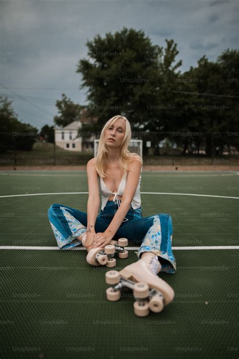 A Woman Sitting On A Tennis Court With Her Skateboard Photo Woman