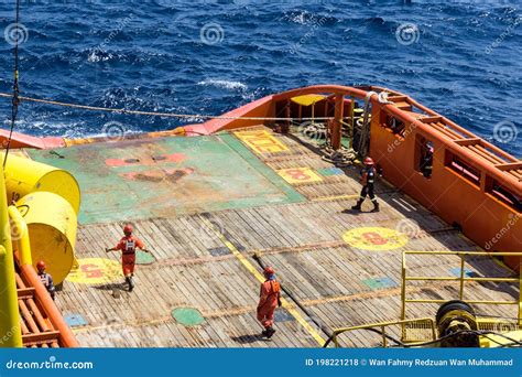 Offshore Workers Or Riggers Assisting Placement Of Anchor Buoy On Deck