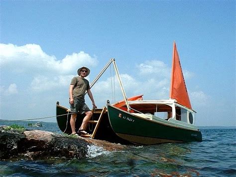 A Man Standing On Top Of A Small Boat In The Ocean Next To A Rock