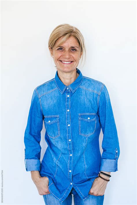 Mature Woman Wearing Denim Clothes Standing Over White By Stocksy Contributor BONNINSTUDIO