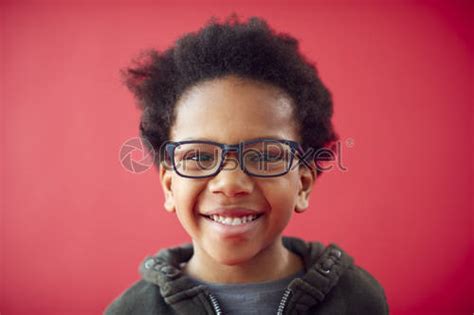 Portrait Of Smiling Young Boy Wearing Glasses Against Red Studio