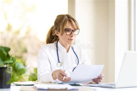 Smiling Female Doctor Sitting At Desk And Working On Laptop Stock Image Image Of Health