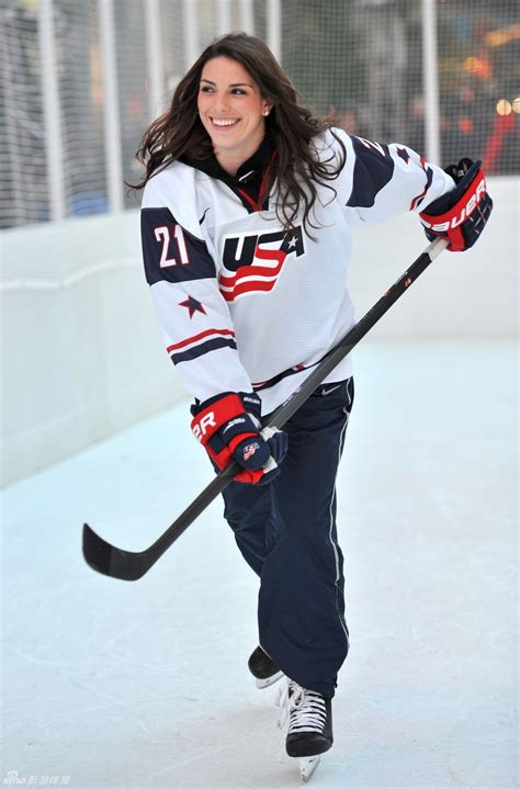 A Woman Is Playing Hockey On An Ice Rink And Smiling At The Camera With