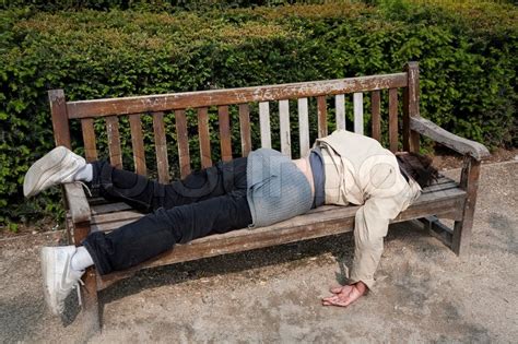 Homeless Unemployed Man Sleeping On Bench In Parisian Park At