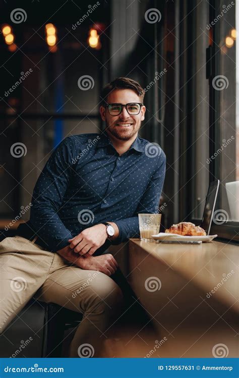 Smiling Man Sitting In Restaurant With Food And Laptop On Table Stock