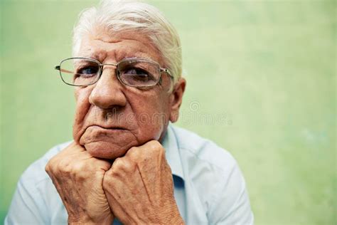 Portrait Of Serious Old Man Looking At Camera With Hands On Chin Stock