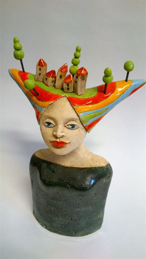 A Ceramic Sculpture Of A Womans Head Wearing A Colorful Hat With