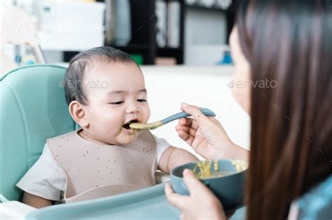 Baby Enjoy And Eating Porridge In High Chair Stock Photo By Kenstocker