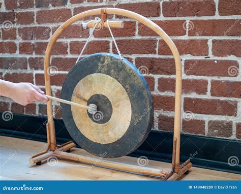 Small Suspended Gong Sitting Hit With Mallet By Hand Of A Woman Stock