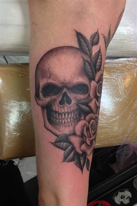 A Skull And Rose Tattoo On The Leg