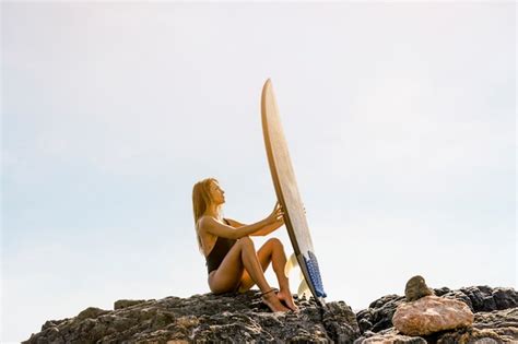 Mujer Sentada En La Orilla Del Mar Con Tabla De Surf Foto Gratis