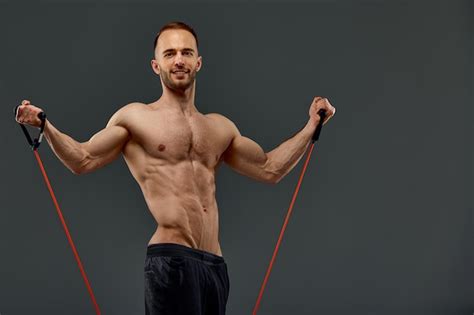Un deportista en topless realiza ejercicios de fitness con banda elástica en un estudio sobre