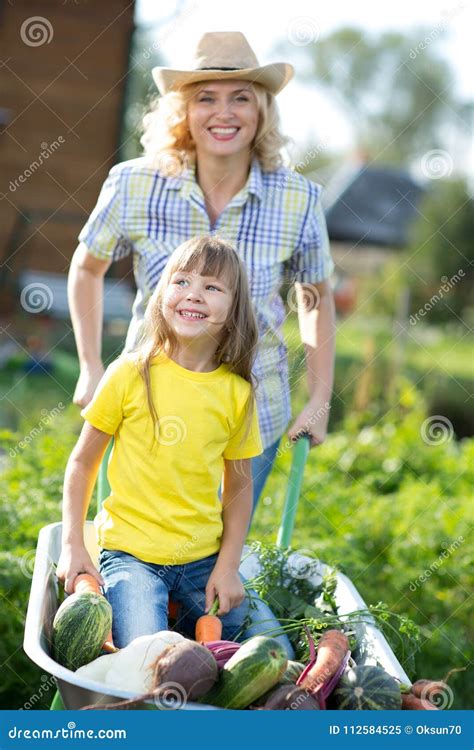 Kid Girl And Mother In Domestic Garden Happy Child And Mom Push The