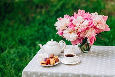 Premium Photo A Vase With Peonies A Teapot And A Cup Of Tea On The Table