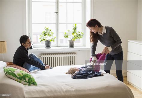 Lesbian Woman Looking At Partner Playing With Girl In Bedroom Photo
