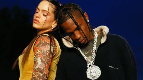 Travis Scott With Female Singer Is Wearing Black Dress Standing In Blue