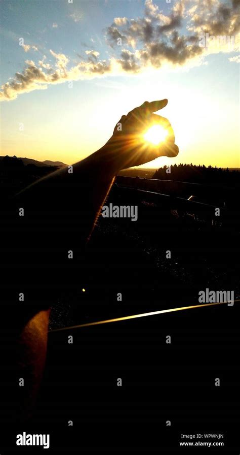 Optical Illusion Of Hand Holding Sun During Sunset Stock Photo Alamy