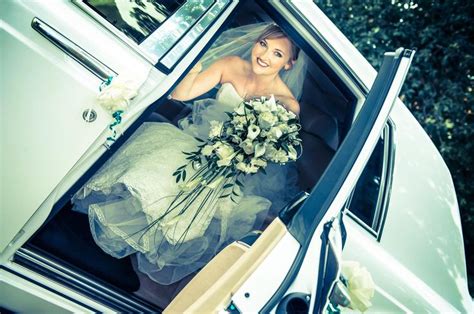 A Bride Sitting In The Back Of A White Car With Her Bouquet On Its Lap