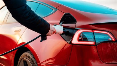 Premium Photo Man Plugging Charging Cable Into A Red Car