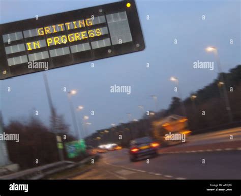 Motorway Sign Gritting In Progress With Gritting Lorry Going Past Stock