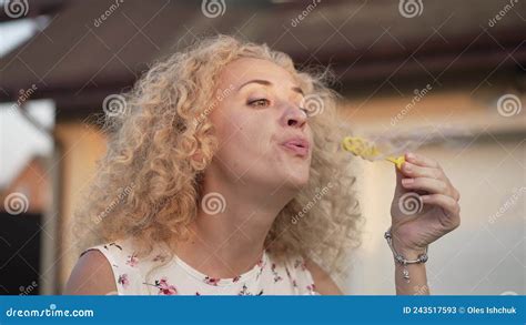 Close Up Portrait Of Smiling Attractive Caucasian Woman Blowing Soap Bubbles At Sunset Outdoors