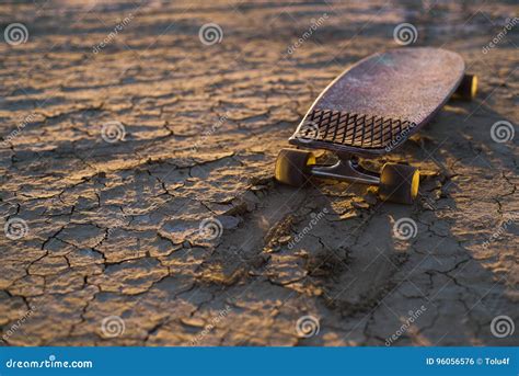 Skateboard Or Longboard Stuck In The Sand In The Desert At Sunset Stock