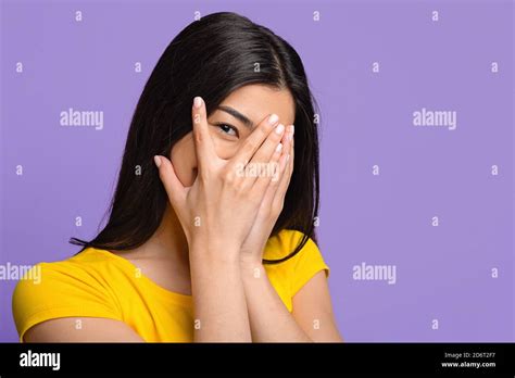 Shy Playful Asian Woman Covering Face With Hands And Peeking Through