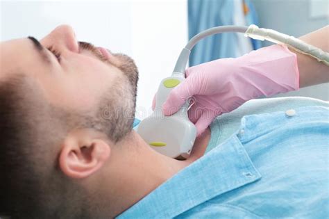 Doctor Conducting Ultrasound Examination Of Patient`s Neck In Clinic