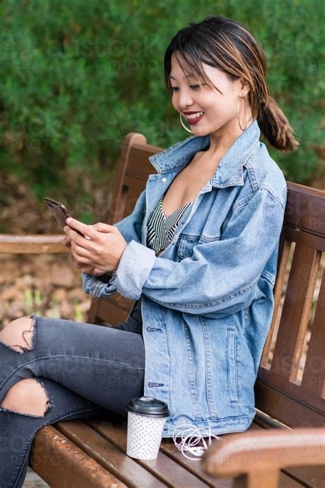 Image Of Pretty Asian Woman Looking At Her Phone And Smiling Austockphoto