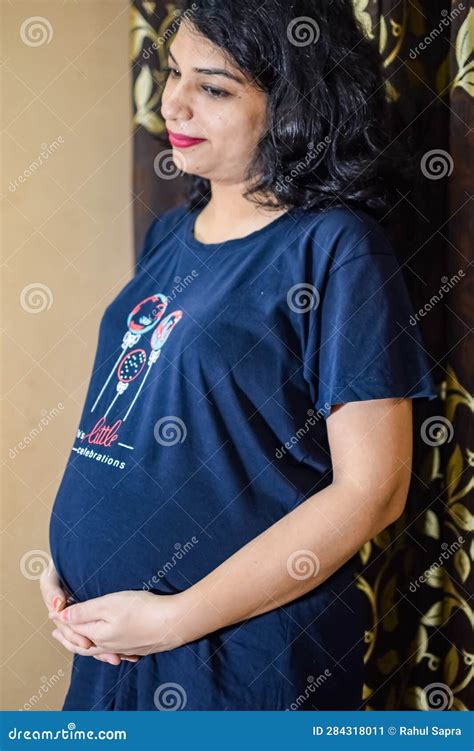 a pregnant indian lady poses for indoor pregnancy shoot and hands on belly indian pregnant