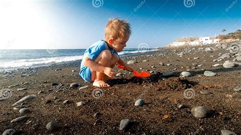 Cute Little Boy Digging Sand On The Sea Ocean Beach And Building Sand
