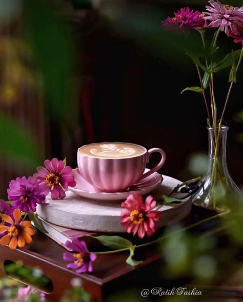 A Pink Coffee Cup Sitting On Top Of A Saucer Next To A Vase Filled With