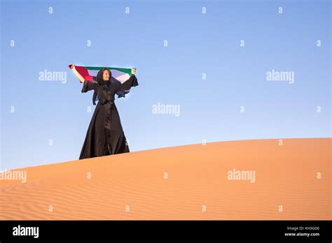 beautiful woman in the national uae dress abaya holding the united arab emirates flag in the