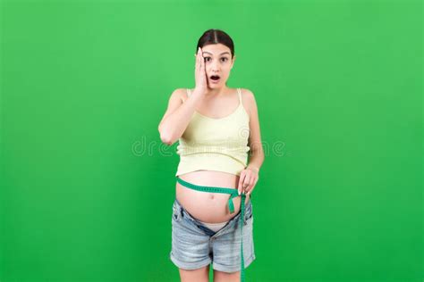 Close Up Of A Pregnant Woman In Opened Jeans Measuring Her Belly With A