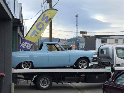 A Flatbed Tow Truck With A Blue Car On It