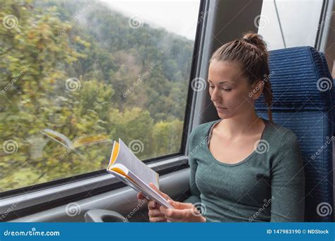 Young Cute Woman Reading A Book While Travelling By Train Stock Photo