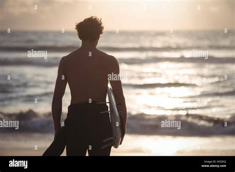 Man Carrying Surfboard Standing On Beach Stock Photo Alamy