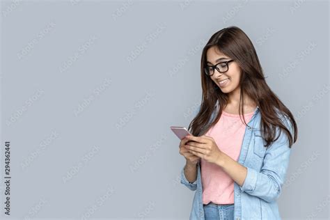 Happy Smiling Young Adult Indian Woman Hold Modern Smart Phone In Hands