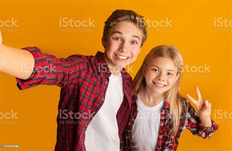Preteen Brother And Sister Taking Selfie Smiling And Showing Peace